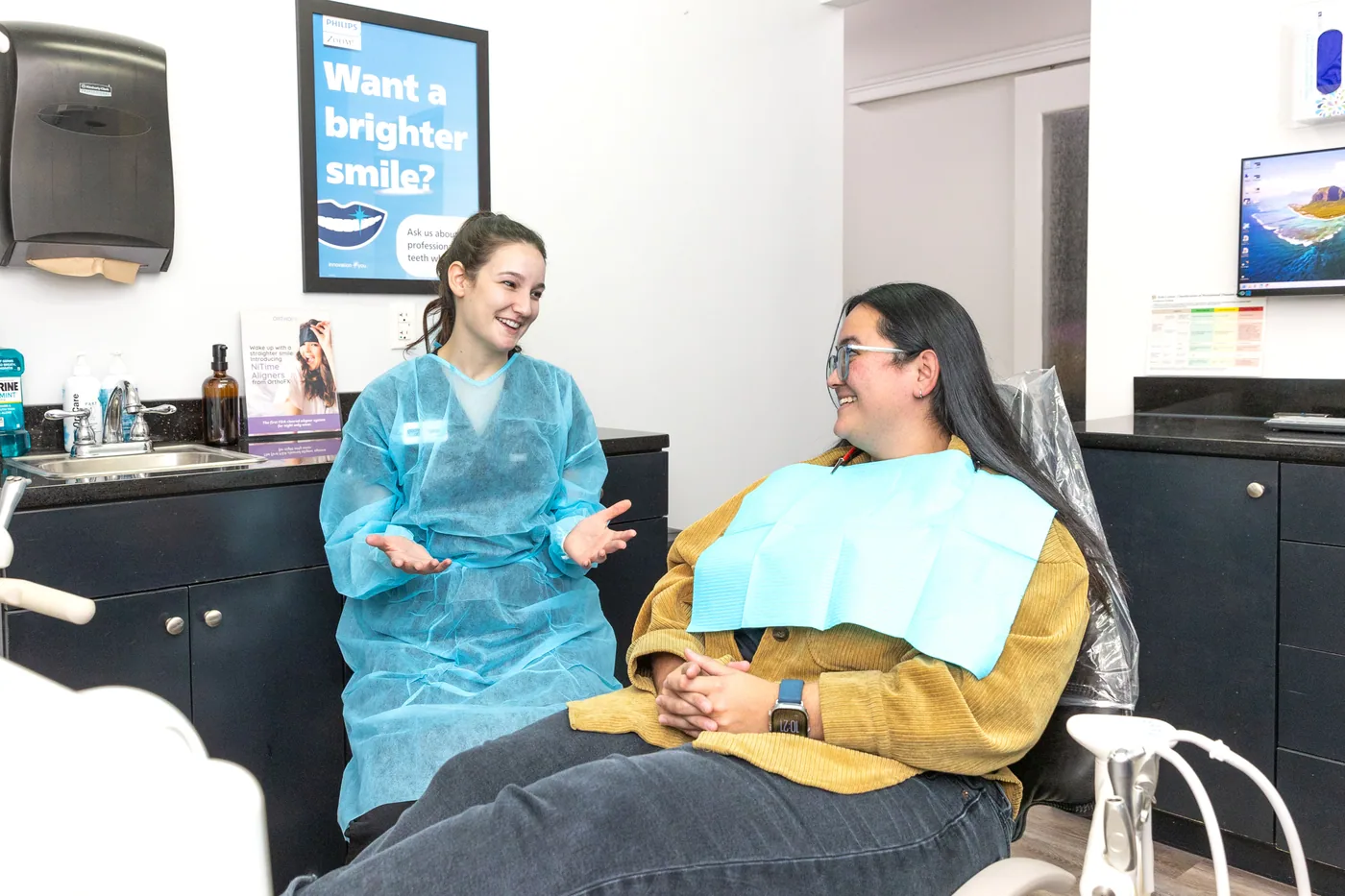 An Embark Dental hygienist talking with a patient in a treatment room