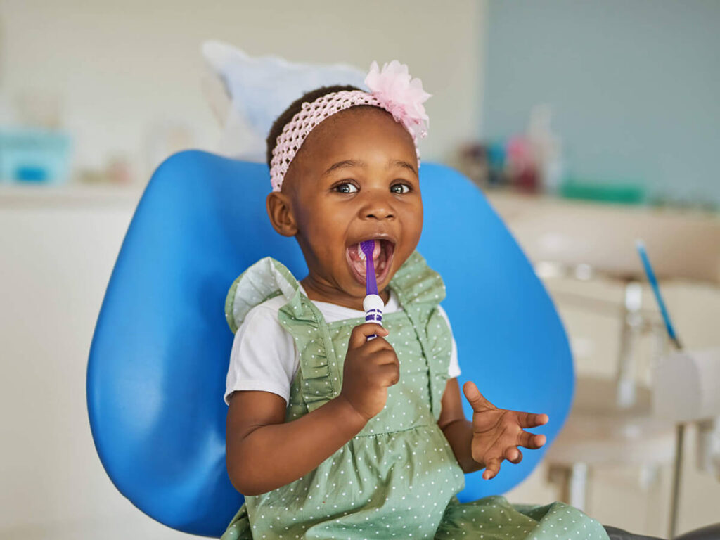 a child brushing her teeth in a dental office chair