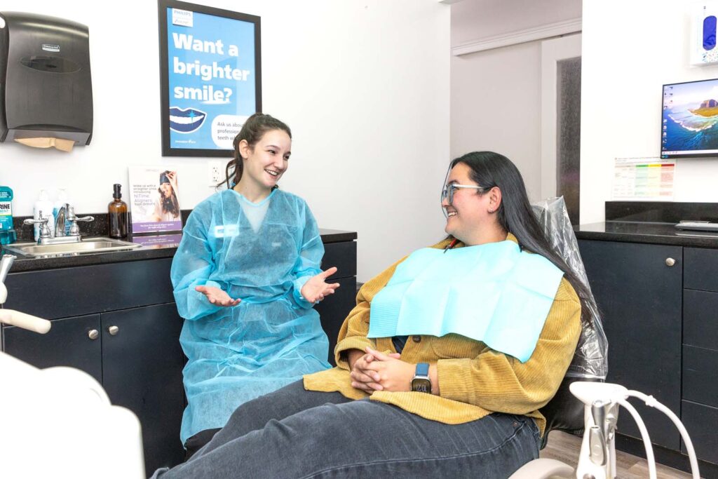 a dental hygienist smiling and talking with a patient